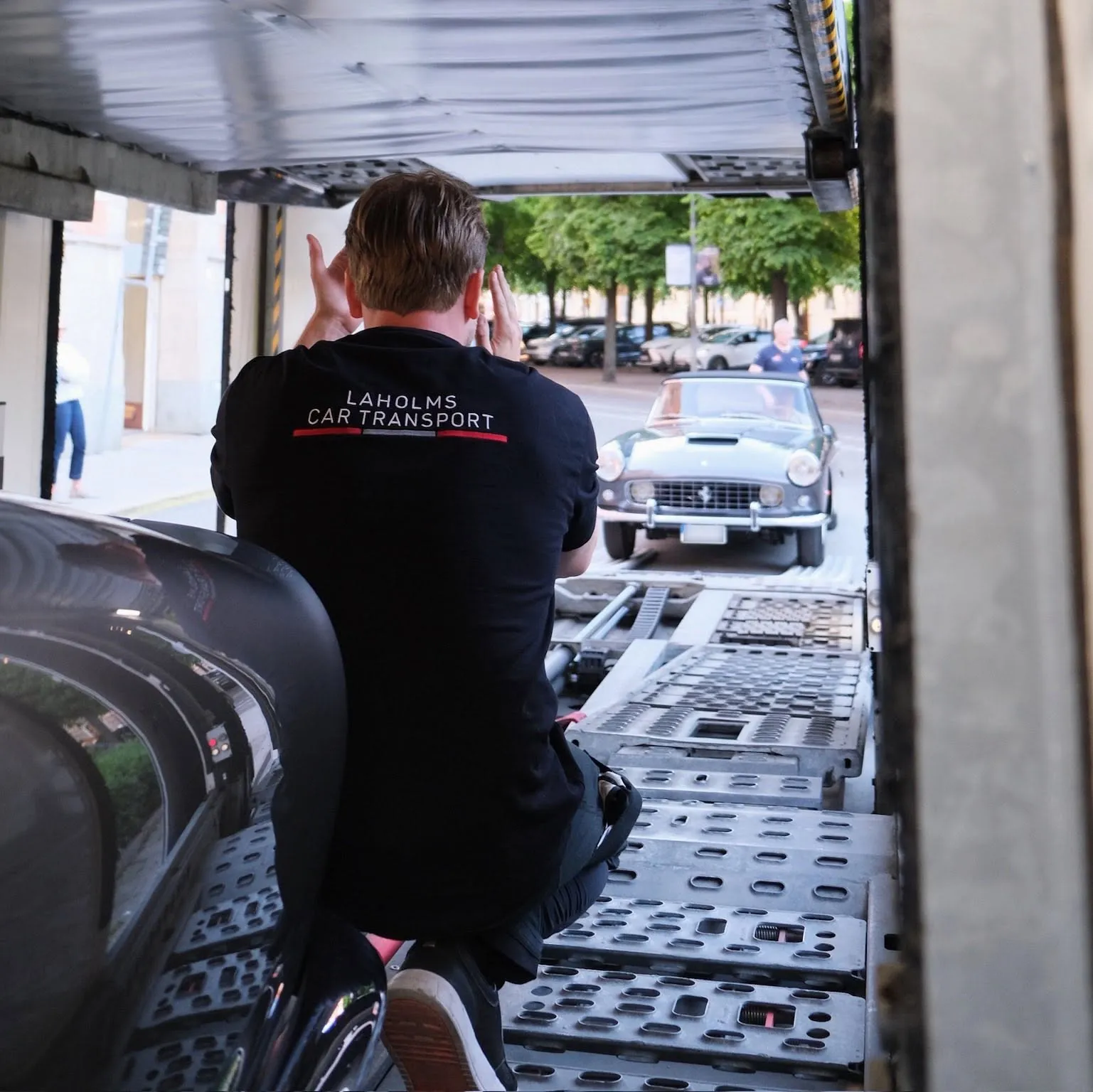 Förare lastar av en klassisk Ferrari på en stadsgata