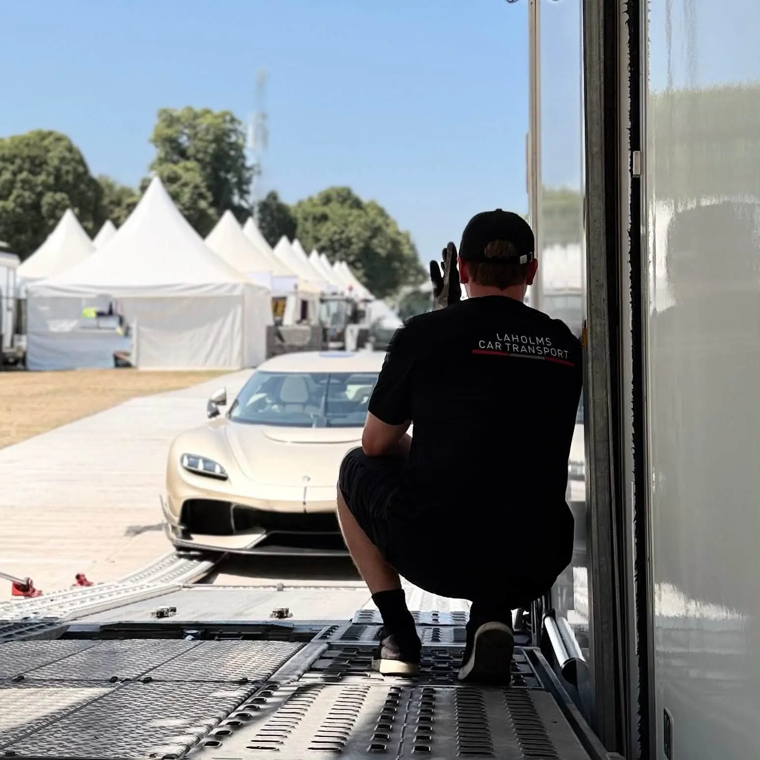 Förare från Laholms Biltransport guidar en hyperbil ut ur den täckta trailern på ett event